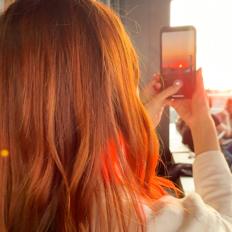 Frau macht Foto von Sonnenuntergang